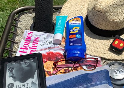 book, suntan lotion, beach hat, on an outdoor table