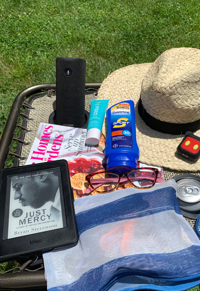 book, suntan lotion, beach hat, on an outdoor table