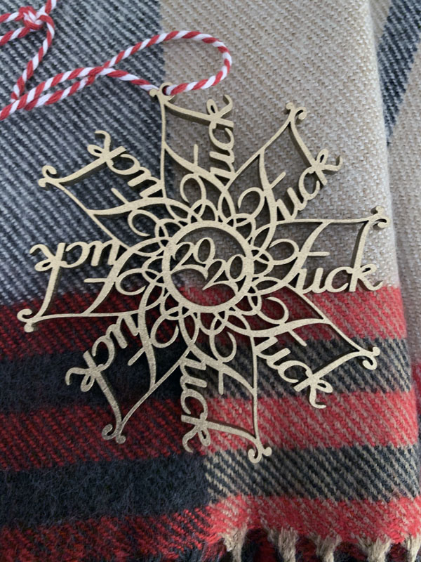 an intricately-carved wooden snowflake with "FUCK' as each arm and '2020' in the middle