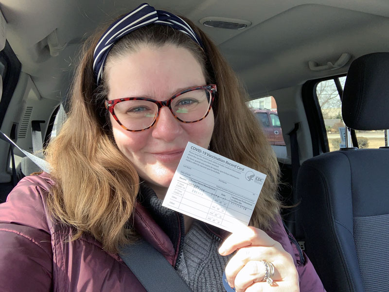 kim, happily holding up a covid vaccination card