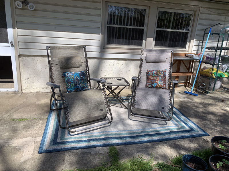 a patio, with 2 chairs, a table, and a patio rug, and a bunch of junk in the background that I can't get rid of.