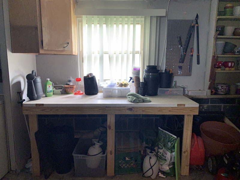 an almost-pristine table with flower pots and other garden supplies around it