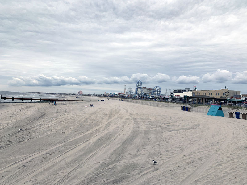 shot of a mostly empty beach, boardwalk behind it, heavy gray clouds