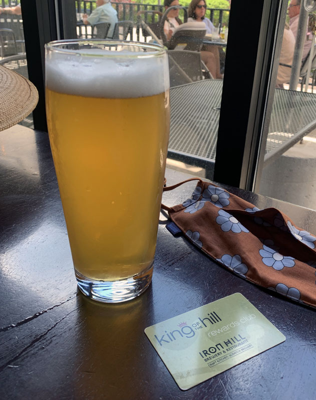 a glass of saison beer, and a mask performatively placed on the table next to it.