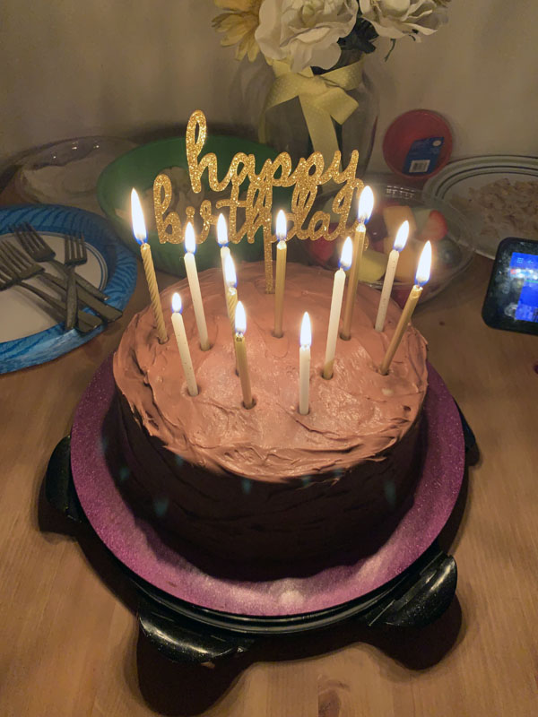 birthday cake with gold candles and a gold 'happy birthday' topper