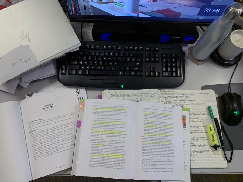 overhead shot of Kim's desk, with 2 textbooks, a notebook, some pens, a  bottle of water, and a candle I bought on clearance and later tossed because it smelled horrible when lit