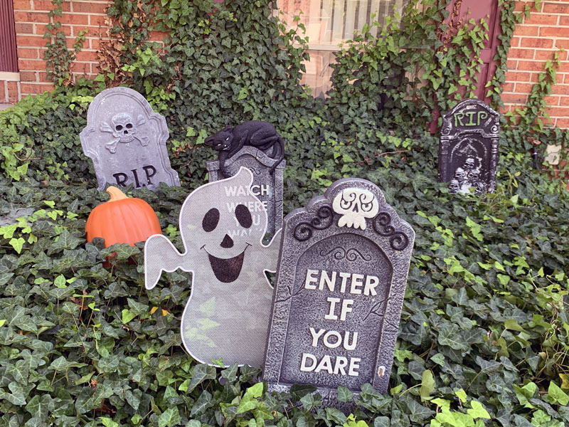 a foam gravestone with a happy wire ghost peeking out from behind it