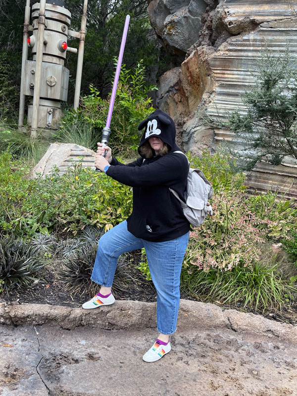 Kim in a Mickey Mouse hoodie weilding a lightsaber