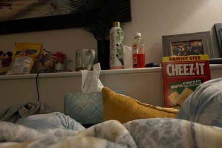 sofa with tissues, dayquil, snacks, and water in the background