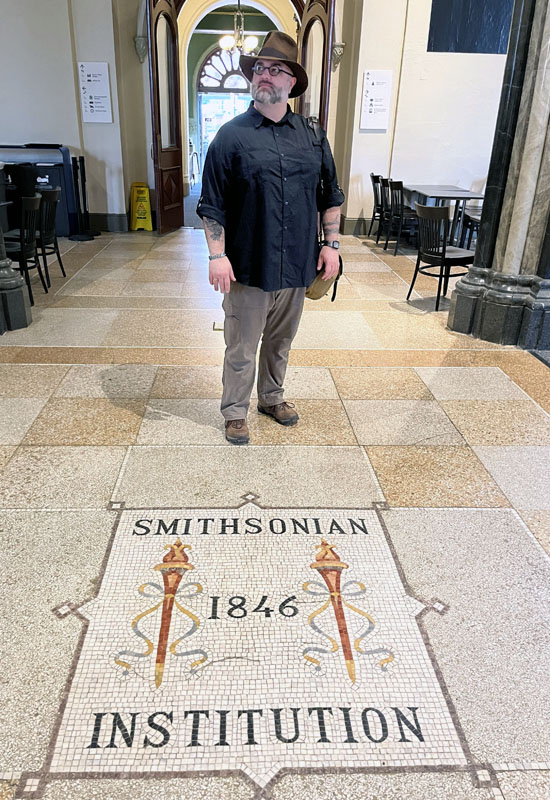 WM, standing in front of a floor tile mosaic that says Smithsonian Institution 1846