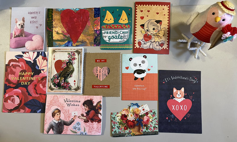 valentine cards spread out on a tabletop. they are all pretty and overwhelmingly red/pink