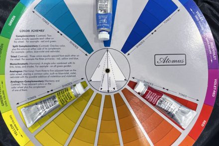 a color wheel with tubes of watercolor pigment artfully placed upon their colors.