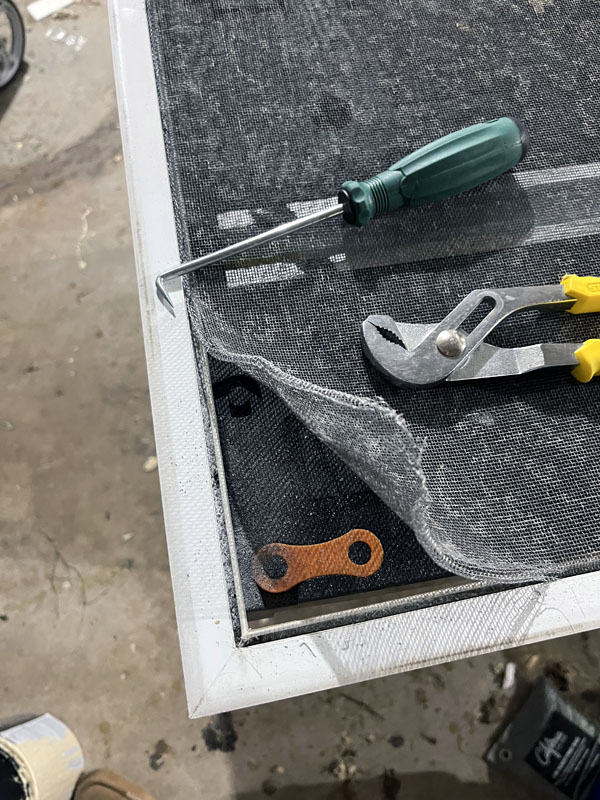 screen door on a work bench with the screen coming out of the corner