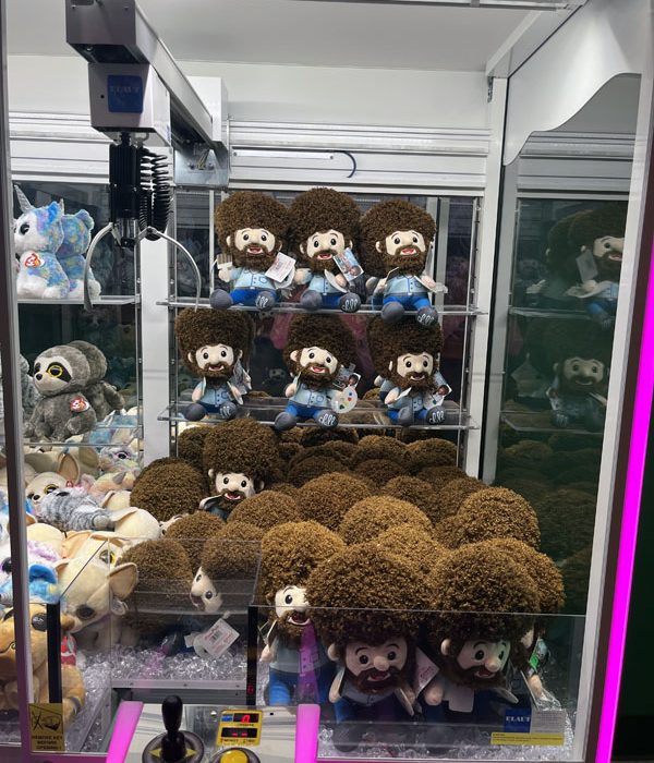 a crane game full of adorable bob ross plushies