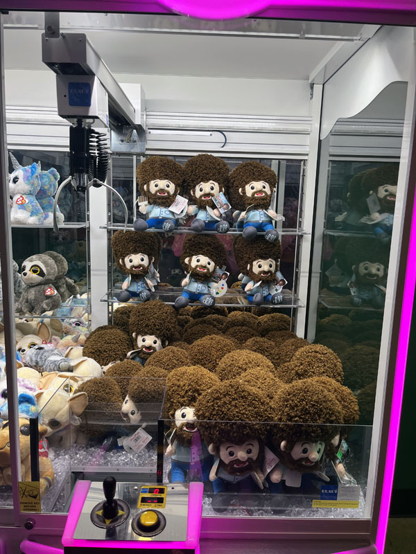 a crane game full of happy little bob ross plushies
