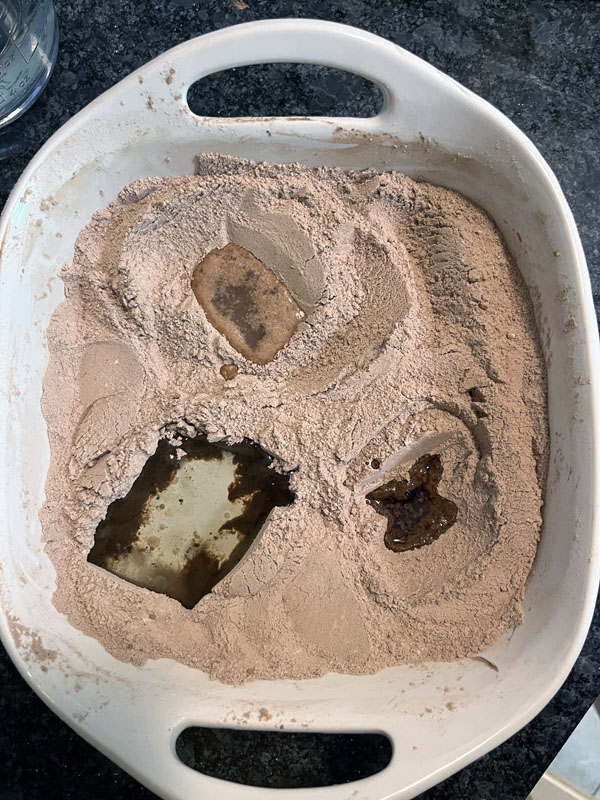 dry cake ingredients in a white baking pan with 3 wells with liquid ingredients