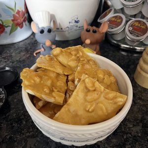 a bowl of peanut brittle, with Remy and Emil figurines watching approvingly