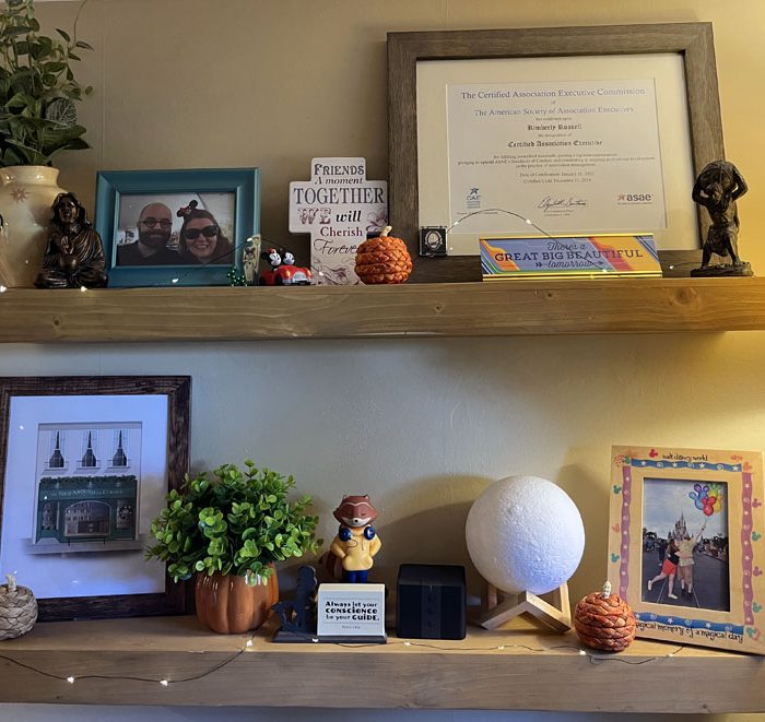 shelves decorated for fall, featuring some small wicker pumpkins, a framed certificate, some photos and knickknacks