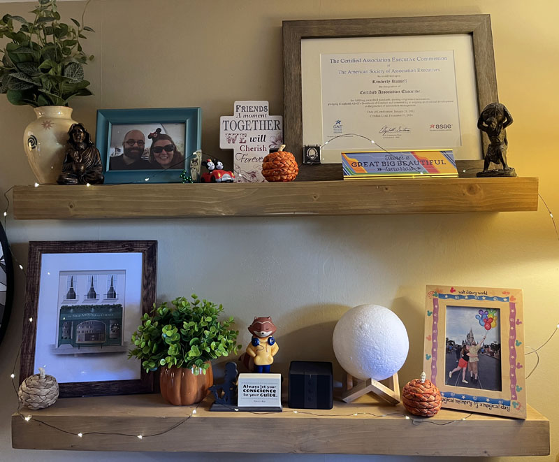 shelves decorated for fall, featuring some small wicker pumpkins, a framed certificate, some photos and knickknacks