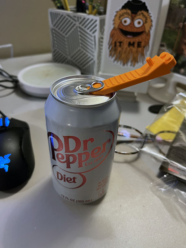 a lego brick removal tool pried beneath the pop tab of a diet dr. pepper can