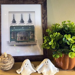 a shelf with a you've got mail print, a ceramic pumpkin, a fake plant in a pumpkin pot, and two DIY'd clay ghosts