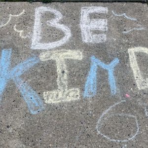 a sidewalk chalk drawing that says "be kind"