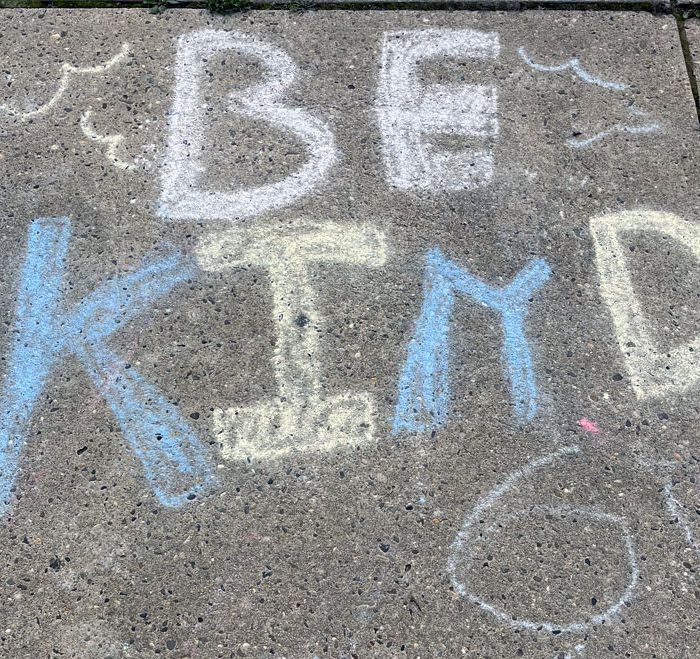 a sidewalk chalk drawing that says "be kind"