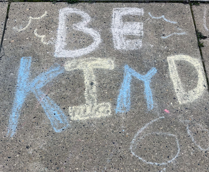a sidewalk chalk drawing that says "be kind"