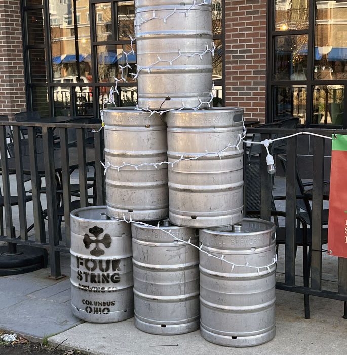 beer kegs stacked in a pyramid with lights around them to resemble a Christmas tree