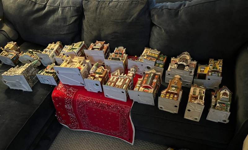 eighteen Christmas Village houses laid out on our sofa. this is not all of them.