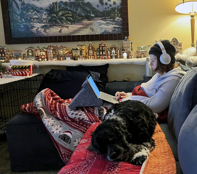 Kim on the sofa, with headphones, surface, dog, blankets.