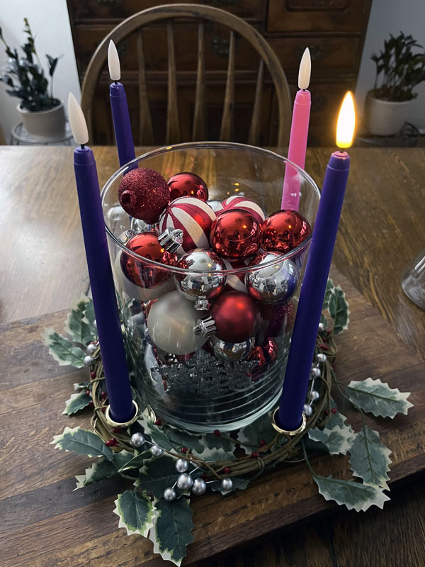 Photo of an Advent Wreath: The first candle, a purple one, is lit.