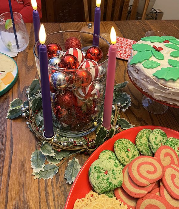 Kim's advent wreath with all 4 candles list, surrounded by cookies and a cake.