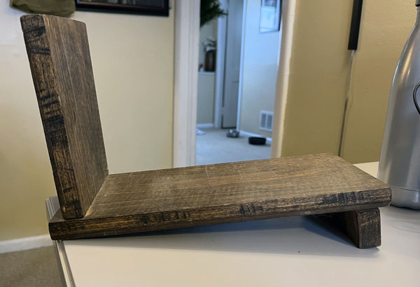 Side view of a slanted wooden bookend with a large piece on the left, and a smaller piece underneath on the right. It is imperfect.