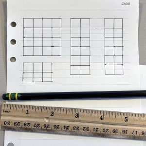 a preliminary garden grid drawn on notebook paper, with a pencil and ruler next to it