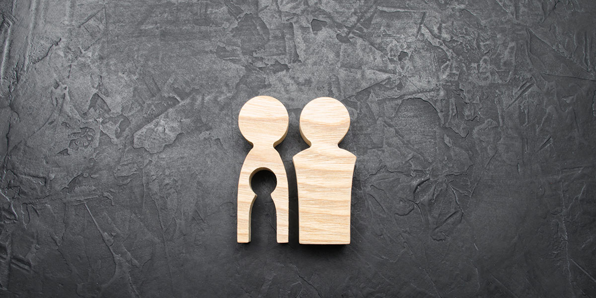 wooden figurines of a traditional womanly-shaped body and a traditional man-shaped body. The woman's figure has a cutout of a child, making that part of her body empty
