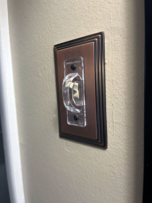 a lightswitch with a plastic cover preventing people from operating the lightswitch