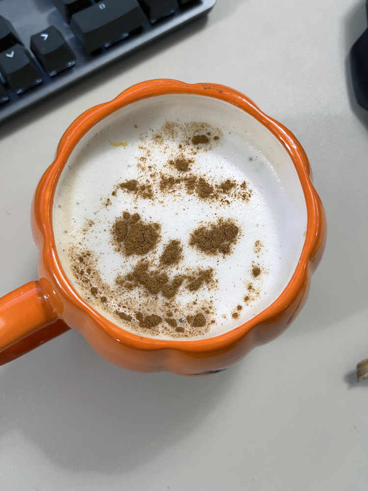 a terrible stencil of a jackolantern on top of a coffee.