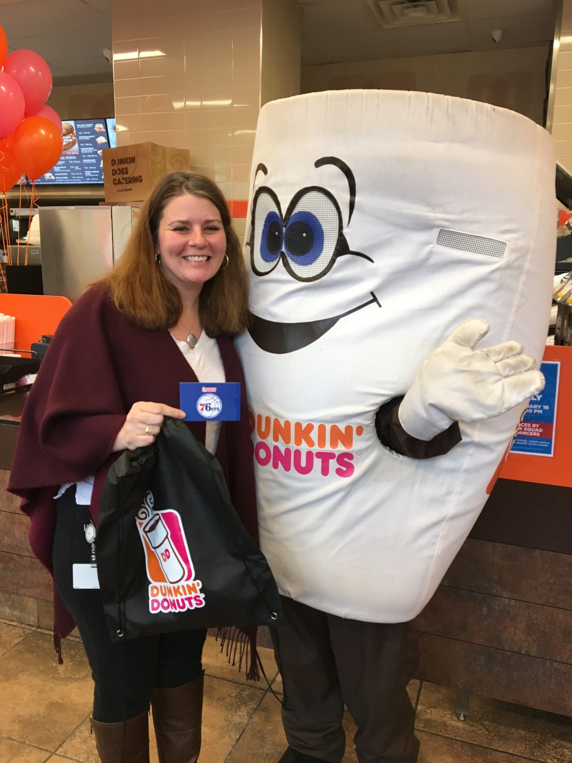 Me in 2018 with a giant Dunkin Donuts coffee cup mascot. I'm holding Dunkin swag and look very 2018.