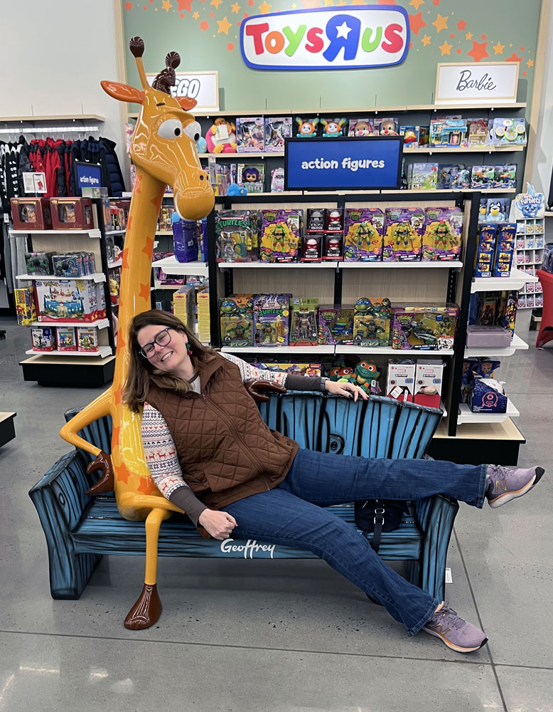 kim snuggling with Geoffrey, the ToysRUS mascot, in a Macy's on Black Friday