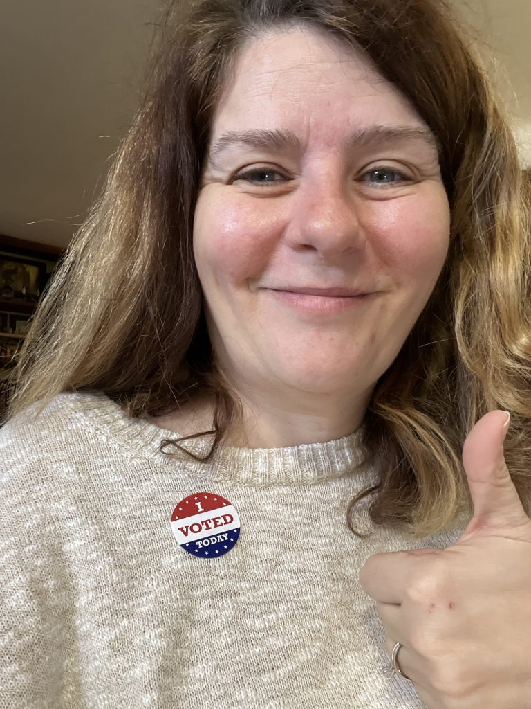 Kim, messy and optimistic, with her thumb up and an "I voted" sticker