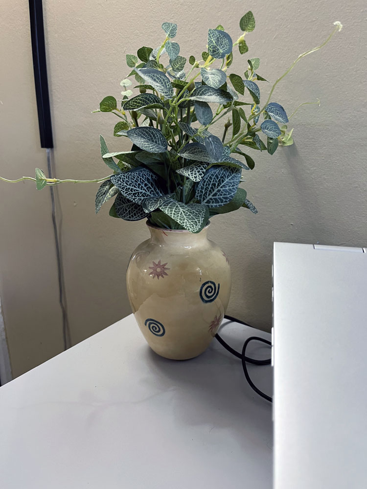 a vase on the corner of the desk. It would be a precarious place to put a vase, but I use museum putty dots