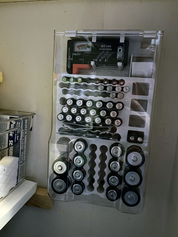 a battery organizer screwd into a closet wall. it's mostly full