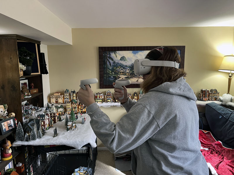 kim in an unflattering gray hoodie, with a VR headset on, guarding herself against an onslaught of fake punches