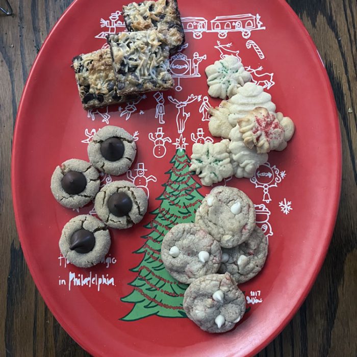 a red tray with four types of cookies on it: bars, butter 'spritz' cookies, white chocolate candy cane cookies, and peanut butter blossoms