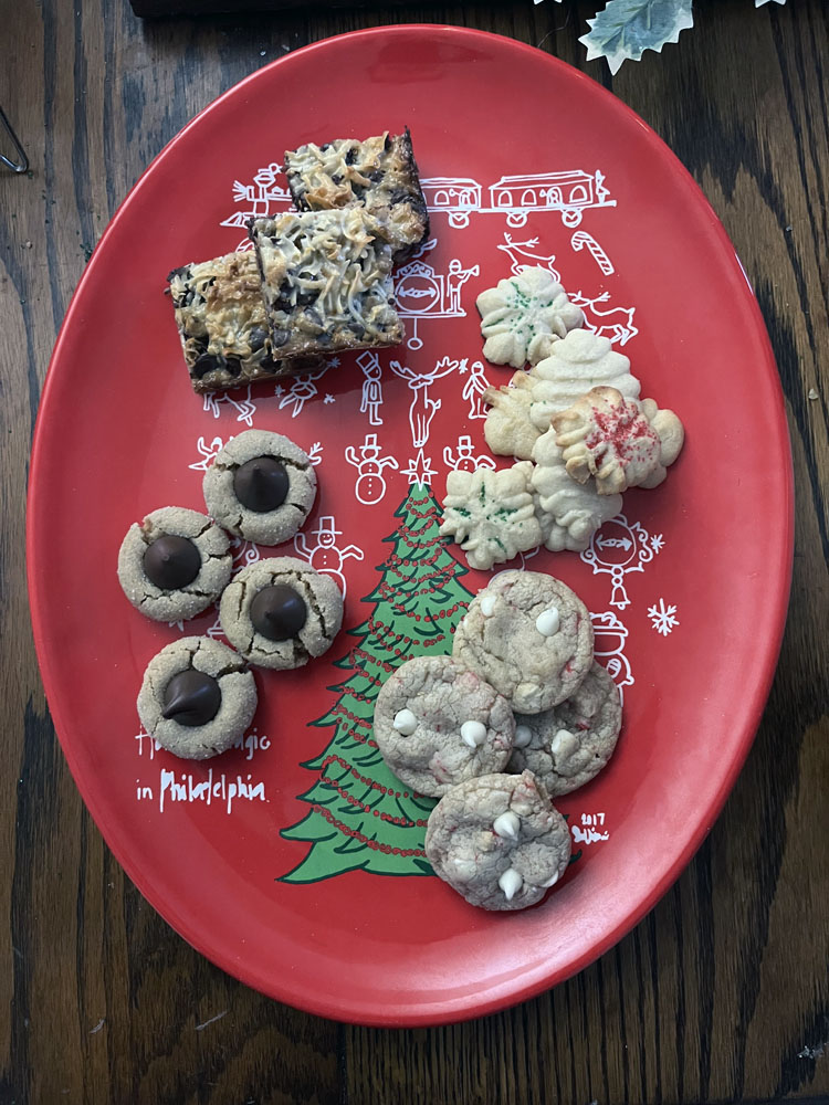 a red tray with four types of cookies on it: bars, butter 'spritz' cookies, white chocolate candy cane cookies, and peanut butter blossoms