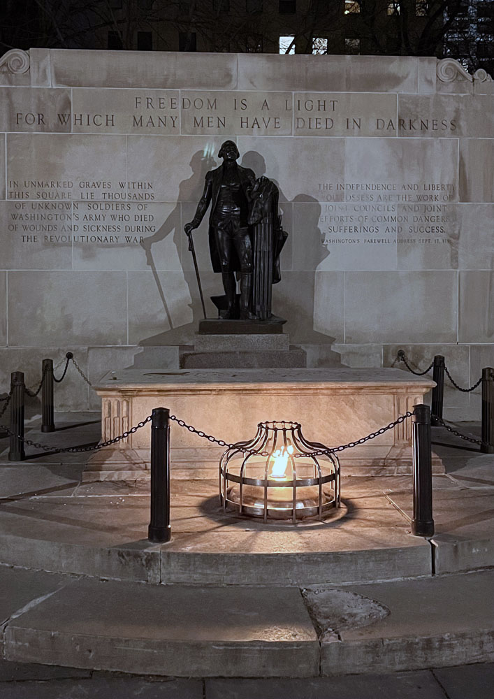 Tomb of the Unknown Revolutionary War Soldier in Philadelphia's Washington Square. The engraved headlines says "Freedom is a light for which many men have died in darkness." There is an eternal flame in front of a statue of George Washington.