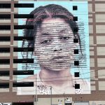 a mural in philadelphia featuring a shoulders-up painting of a young Black woman with the text of the declaration of independence over it. it's called 'declaration'