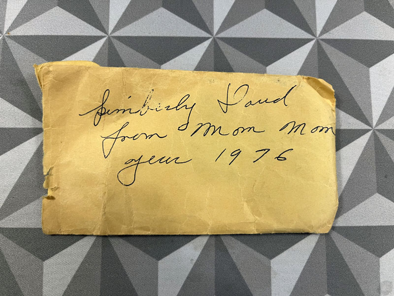 a crumpled brown envelope with shaky cursive handwriting reading: kimberly Dowd from Mom Mom year 1976