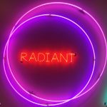 a neon sign. there is are two purple neon circles and inside those circles is the word radiant in red neon